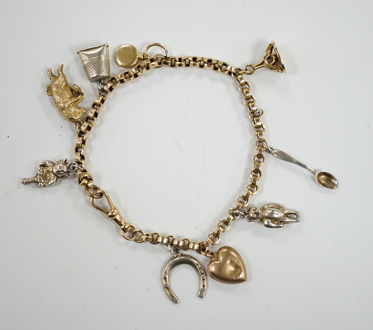 A 9ct charm bracelet, hung with nine assorted yellow and white metal charms including sterling and 10k, 16cm